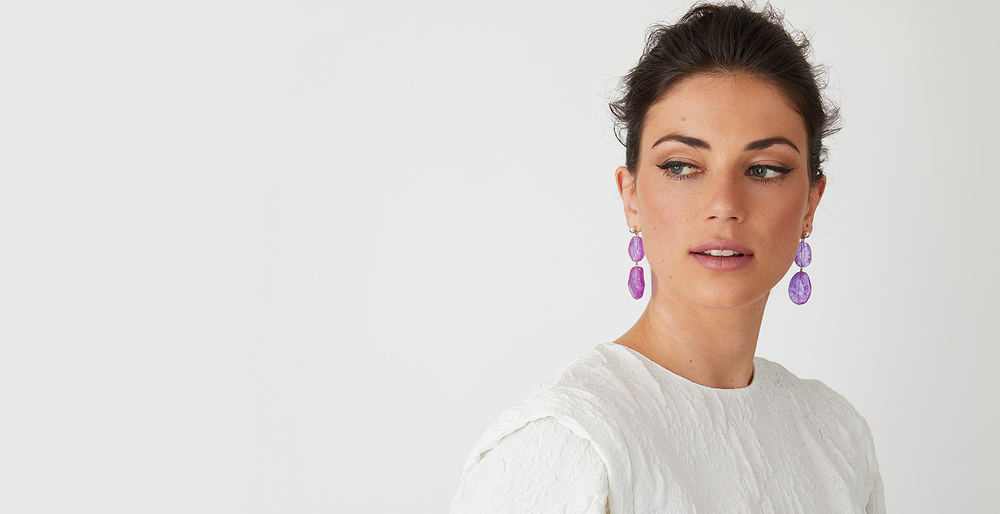 Purple resin statement earrings worn by a model in a white top