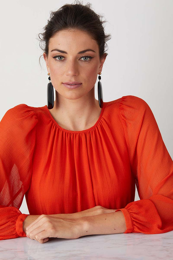 Black statement earrings worn by a model in a flowy colourful dress