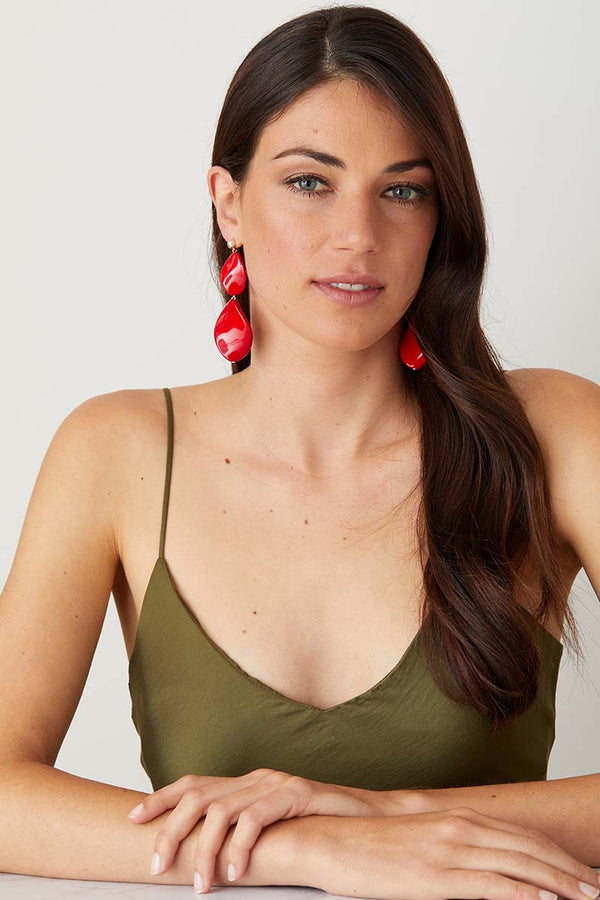 Red statement earrings worn by a model in a green summer dress