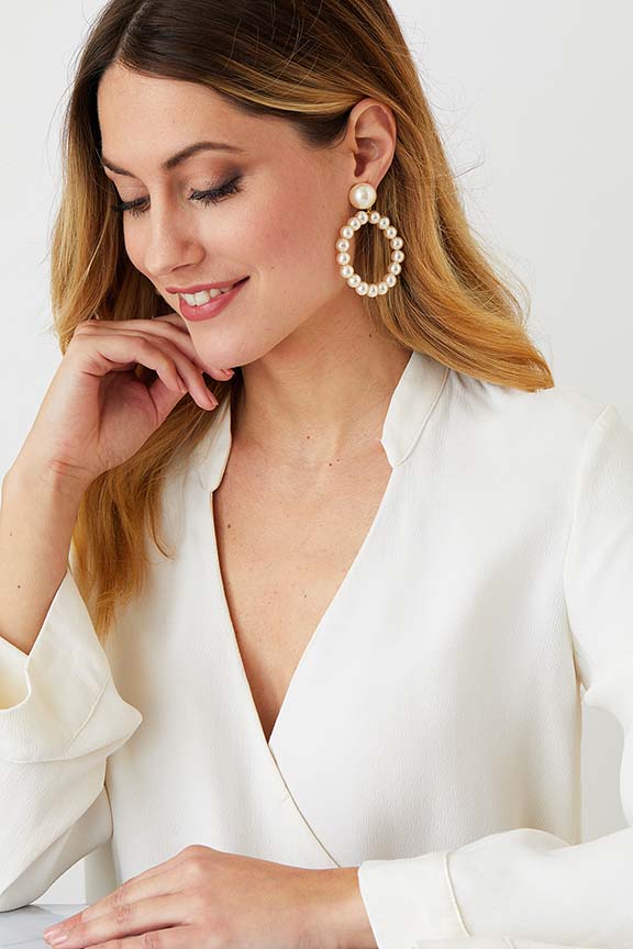 Pearl hoop clip on stud statement earrings worn by a model in a white blazer