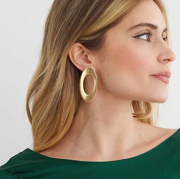Gold hoop statement earrings worn by a model in a green silk top