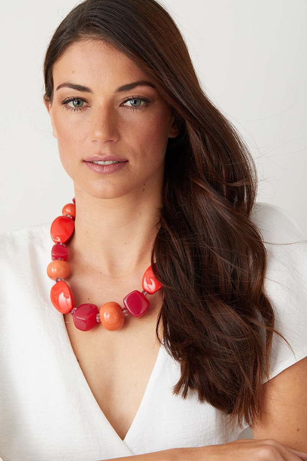 Pink orange red statement necklace worn by a model in a white top