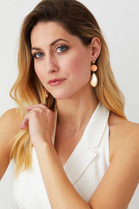 Pink burl gold statement earrings worn by a model in a white double-breasted suit blazer