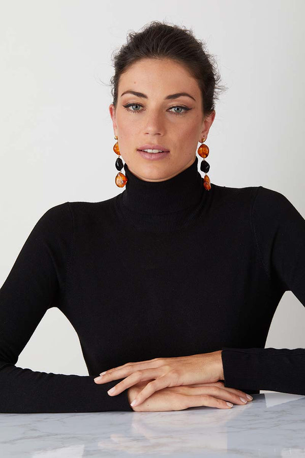 Amber black statement earrings worn by a model in a black turtleneck