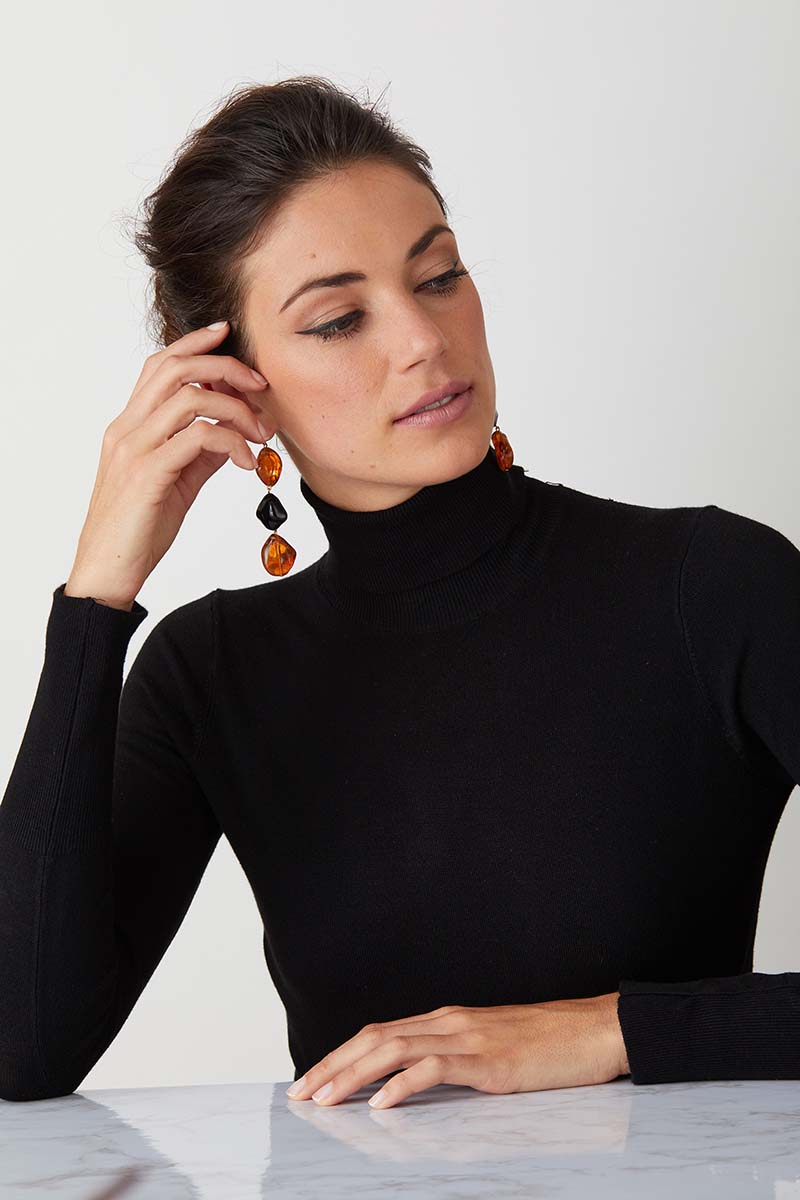 Amber black resin statement earrings worn by a model in a black turtleneck