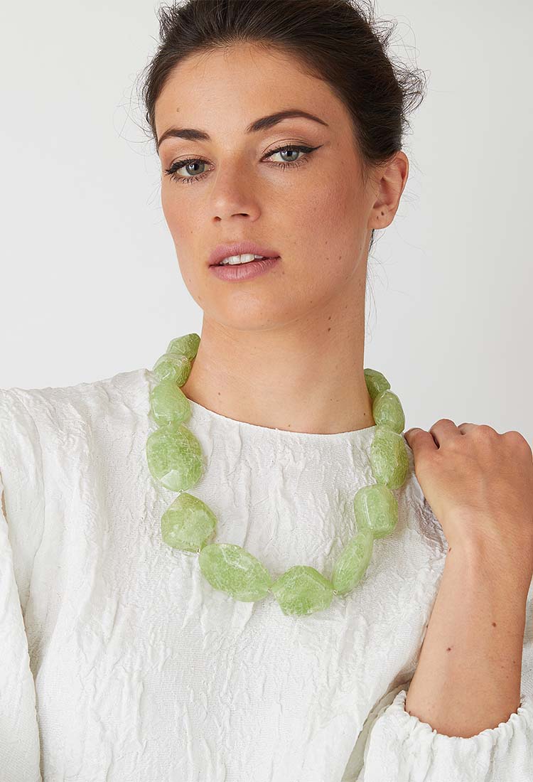 Light green statement necklace worn by a model in a white top