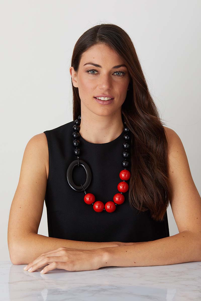 a luxury Italian black and red statement necklace made of resin worn by a woman in a black evening dress