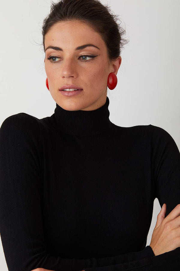 Red clip on button statement earrings worn by a model in a black turtleneck