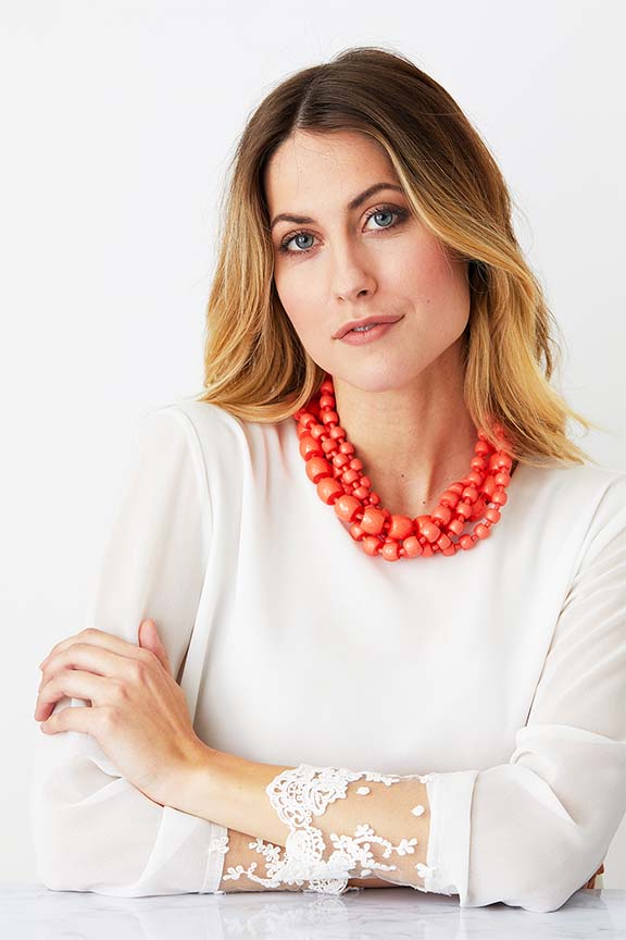 Orange coral torchon statement necklace worn by a model in a white top