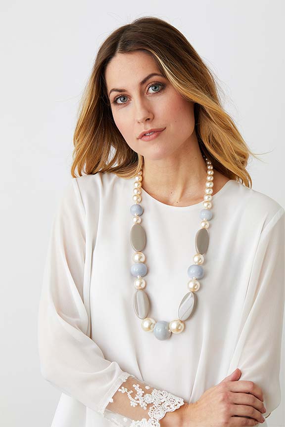 Pearl beige long statement necklace worn by a model in a white lace top