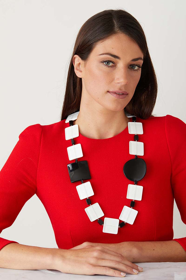 White black statement necklace worn by a model in a red elegant dress