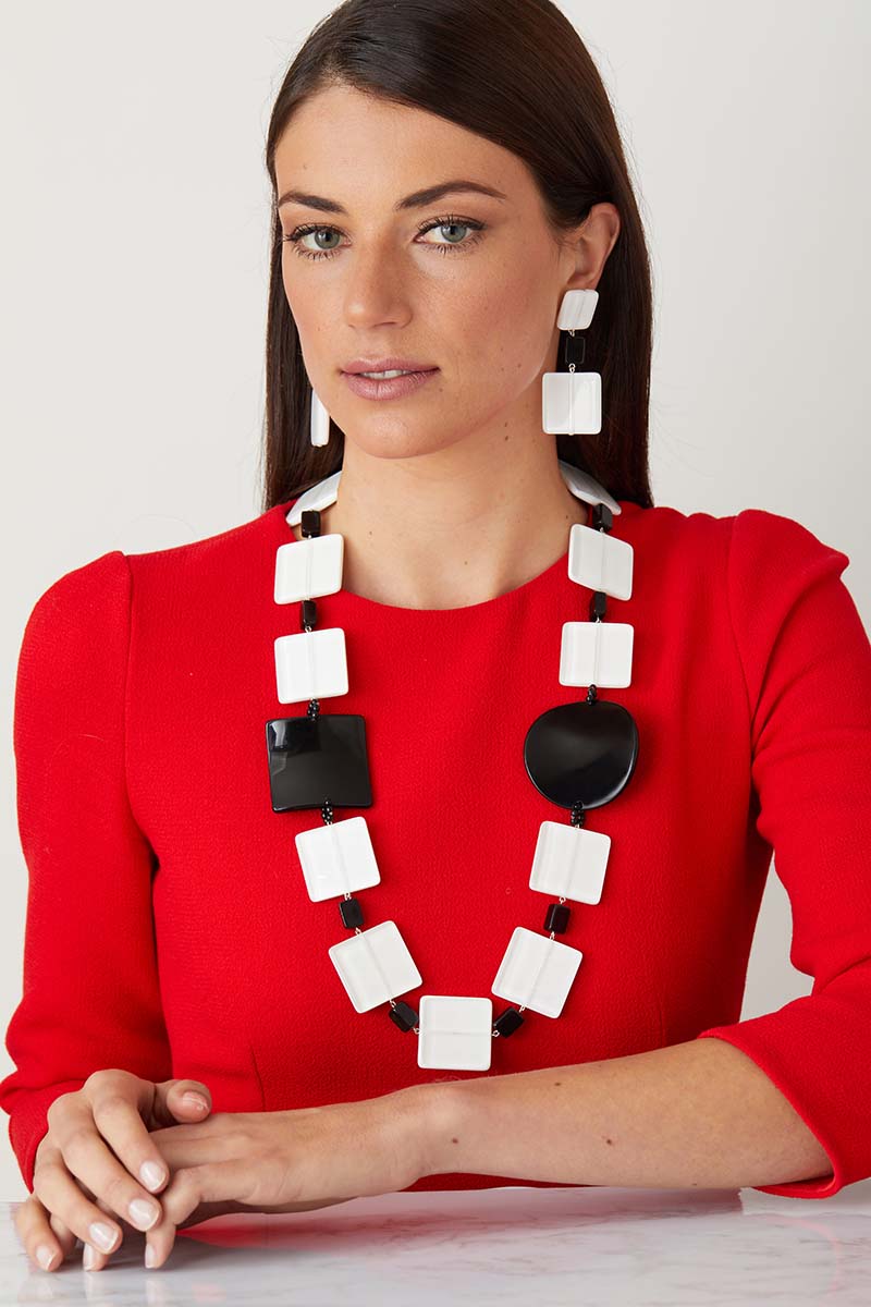 White black statement necklace worn by a model as a pendant set, in a red dress