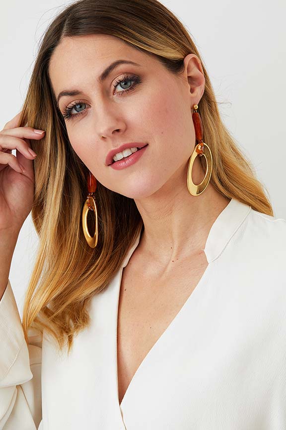 Gold amber drop statement earrings worn by a model in a white blazer, made of resin 