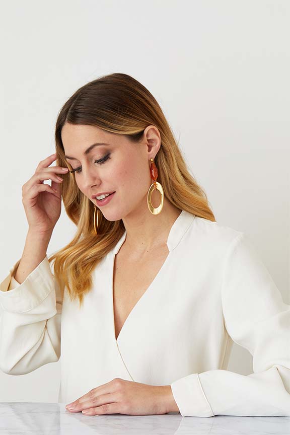 Gold amber drop statement earrings worn by a model in a white top