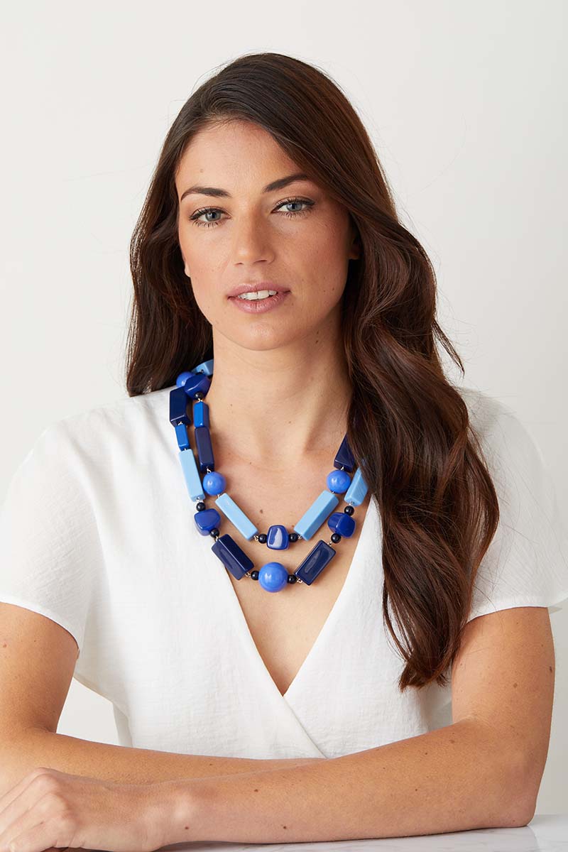 Blue statement necklace worn by a model in a white top