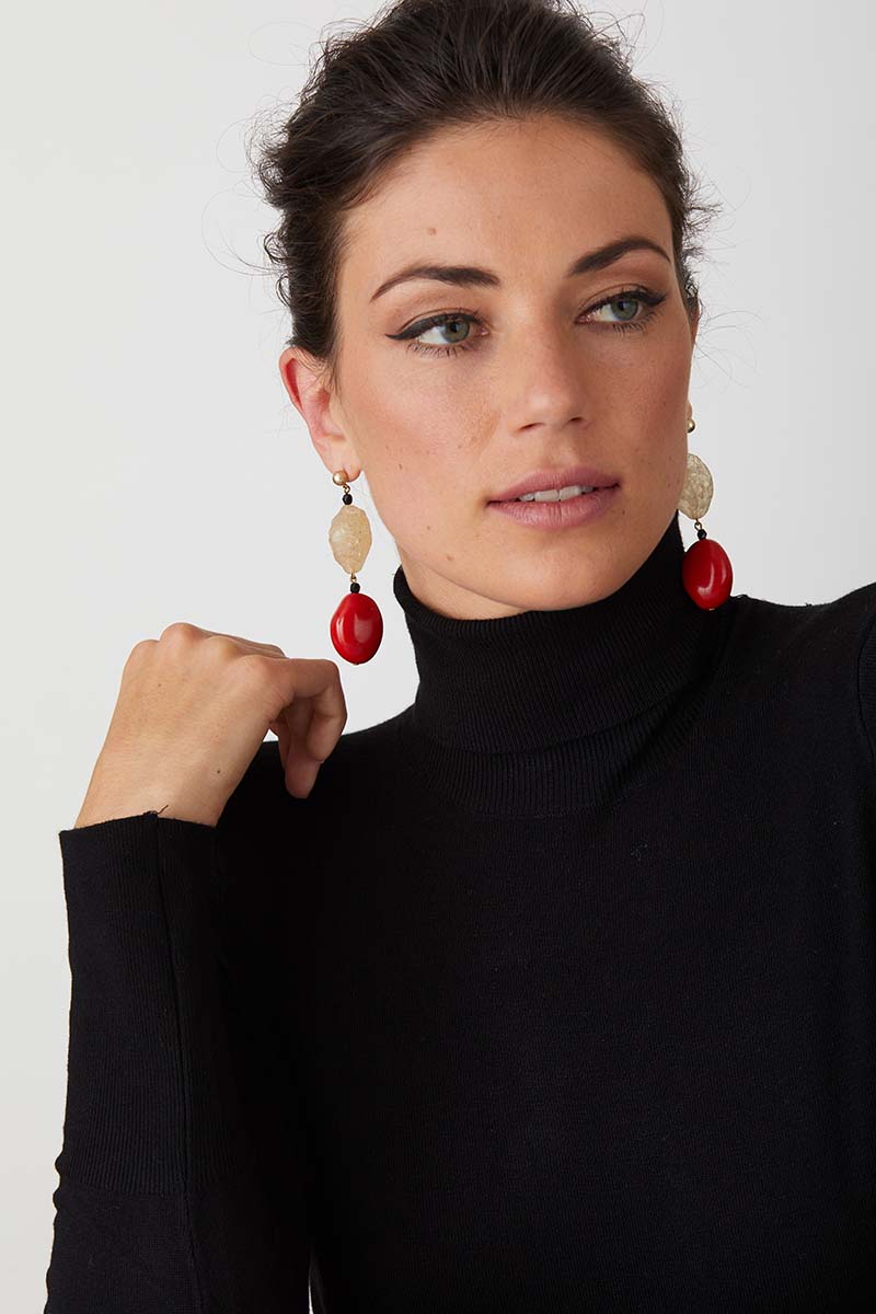 Red coral black statement earrings worn by a model in a black turtleneck