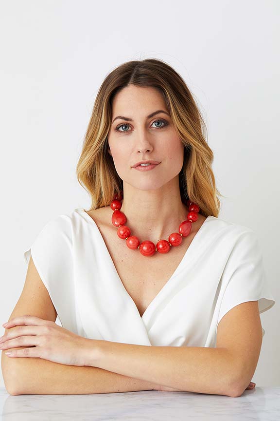 Orange coral gold statement necklace worn by a model in a white evening dress