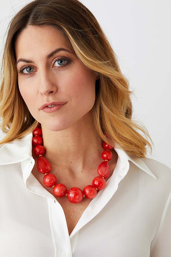 Orange coral gold statement necklace worn by a model in a white collared silk shirt