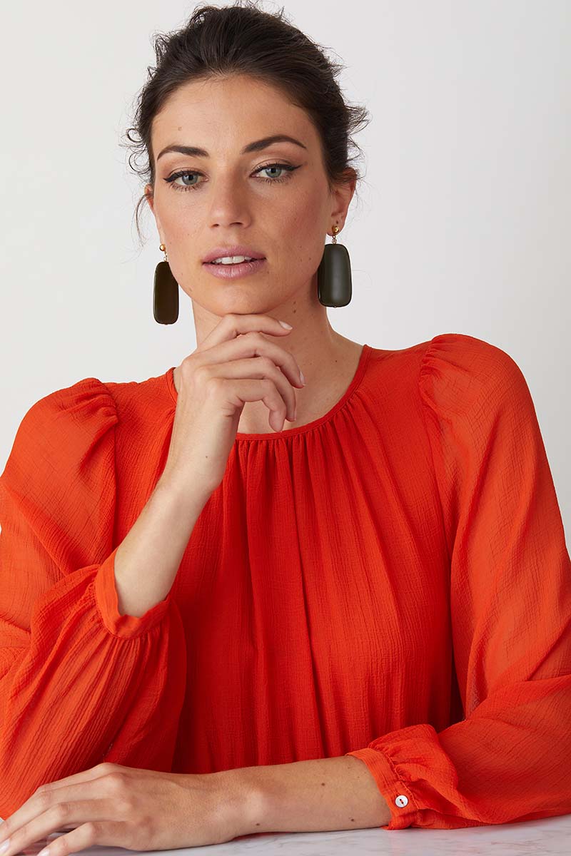 Green statement earrings worn by a model in a red summer dress