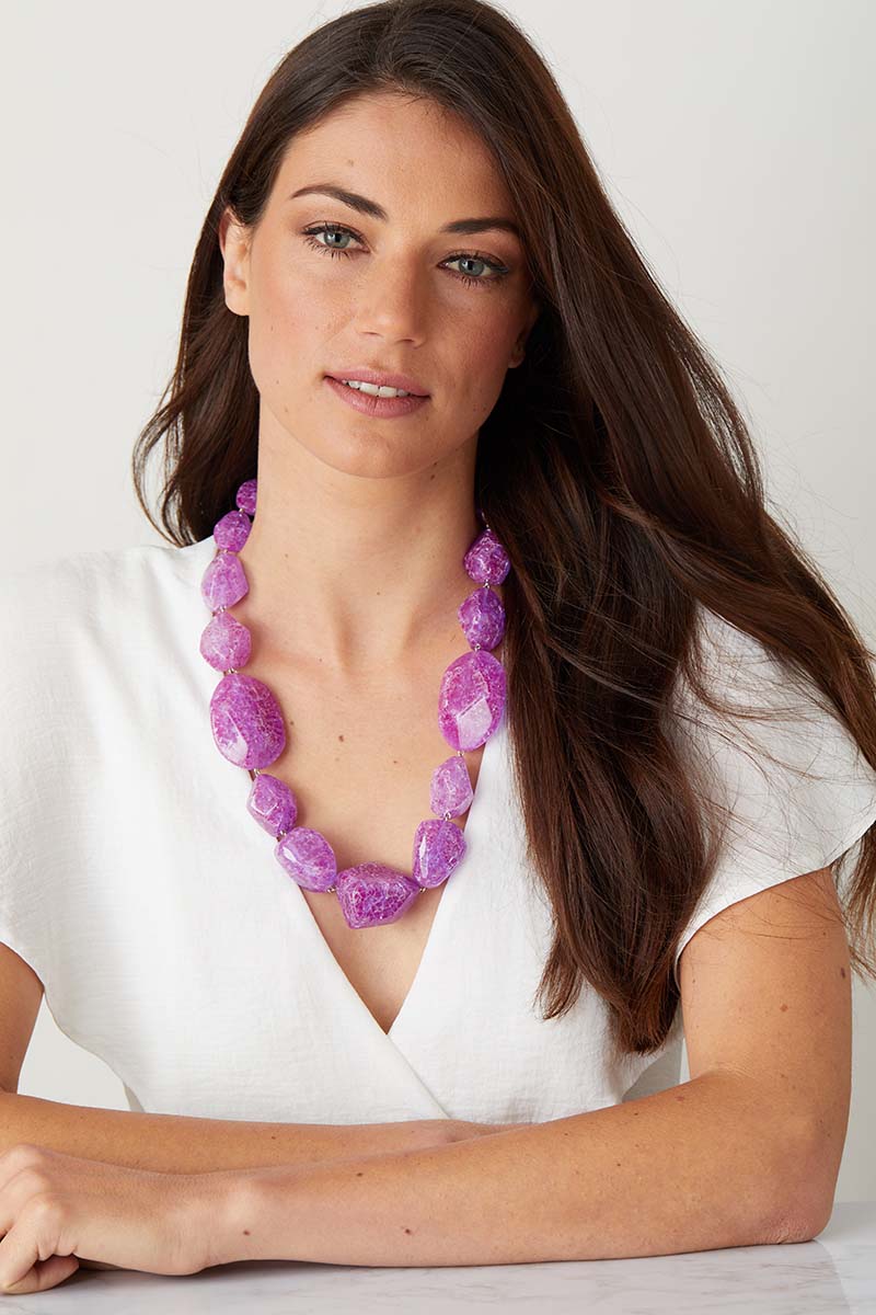 Purple resin statement necklace worn by a model in a white summer top