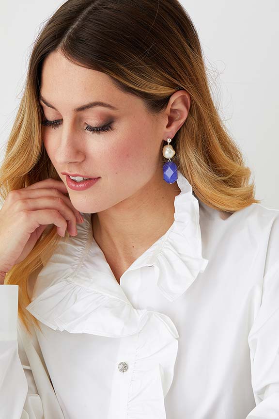 Baroque pearl blue statement earrings worn by a model in a ruffled collared white shirt